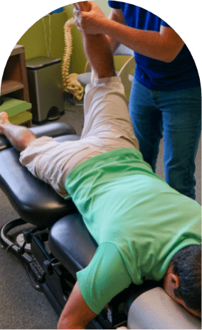 Man on chiropractic table with one leg lifted